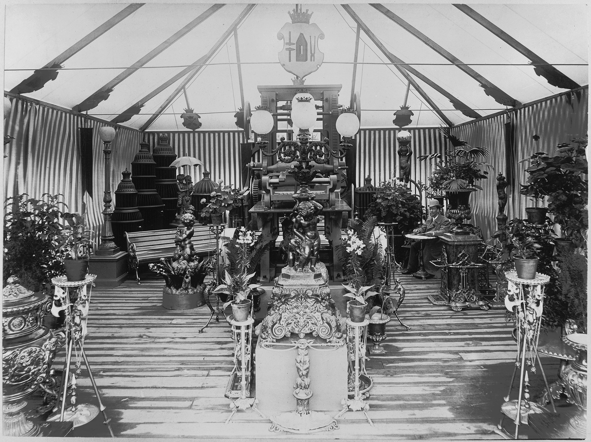 Blomsterarrangemang i monter om Bolinders gjutjärnsprodukter på utställning i Göteborg 1891.