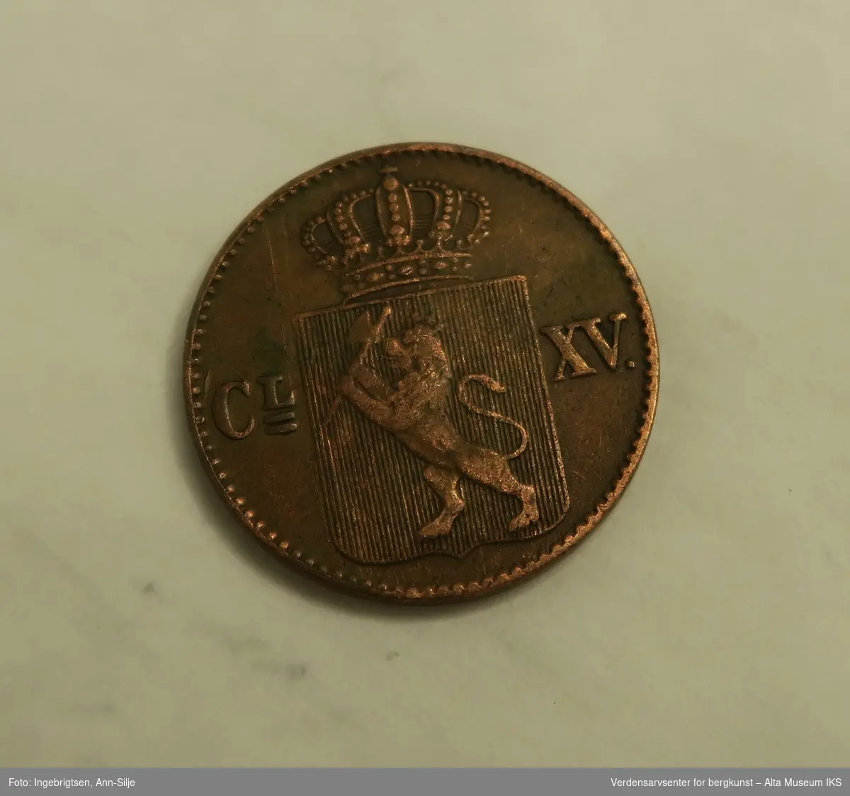 Form: Rund mynt med motiv av Riksvåpen med løve og krone.