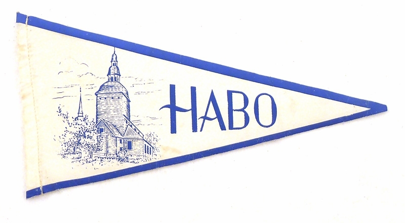 Vit souvenirvimpelmed tryck i blått.
"Habo" samt bild på Habo kyrka.