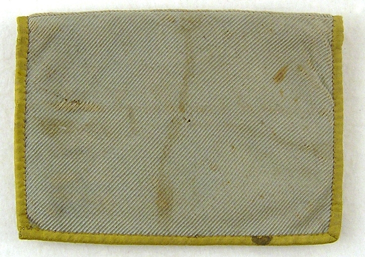 Plånbok av ljust grönblått siden, dubbel, blårött bomullsfoder samt kantad med gult sidenband runtom. I ena facket isydd läderbit med isnkription: Löfvenskiöld Mariestad. Smutsig.