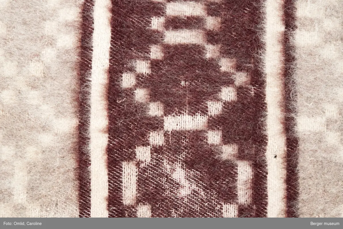 Teppeprøve med åttekantet rutemønster, med bord i liknende mønster innrammet av to paralelle striper. Teppet i lyse beige toner, borden i mørk burgunder