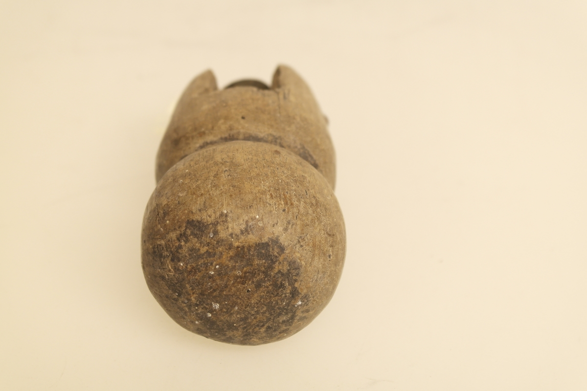 Dørhåndtak av eik og messing. Håndtaket er utformet som en kjegle med innsnevring. Messinghylse til vridepinne inni håndtaket.