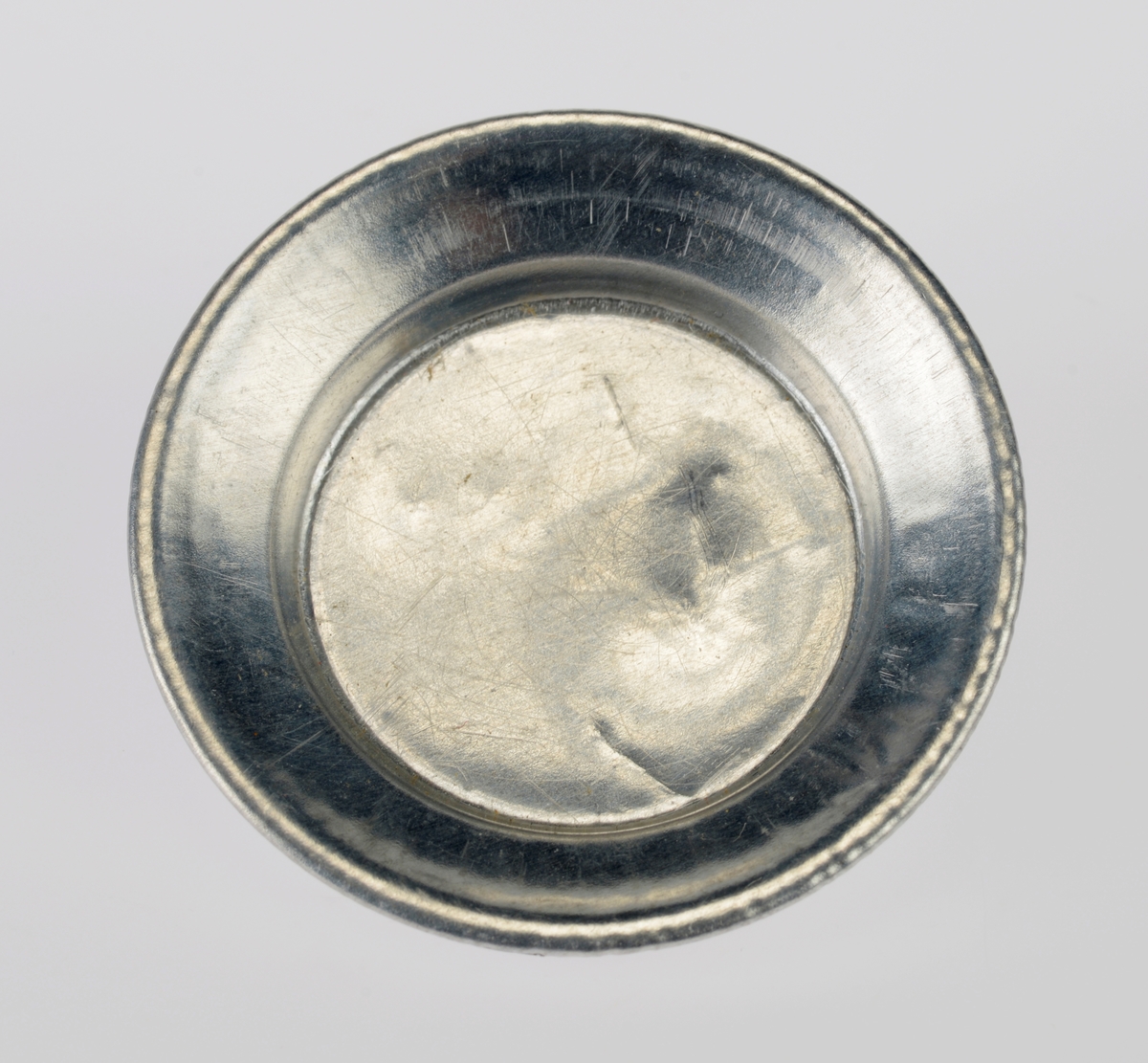 Et kjøkkensett som er montert i en liten pappeske med lokk. Settet er trolig fabrikkprodusert. Gjenstandene er undernummerert 01-10.
FTT.54457.01: En kasserolle med lokk laget av blikk. I hver side av kasserollen er det relativt store svartmalte håndtak av metall, og på lokket er det en treknott som også er svartmalt. Håndtakene og knotten er loddet på. Kasserollen er trolig valset.
FTT.54457.02-03: To identiske tallerkener laget av blikk. De er runde med en bred rand.
FTT.54457.04-05: To identiske kniver laget av metall, og de er antageligvis støpt. Håndtaket har prikker langs kanten som står opp fra metallet, og i midten er det en opphøyet stripe av metall. Knivbladet er relativt bredt og avrundet i tuppen. 
FTT.54457.06-07: To identiske skjeer laget av metall, og de er antageligvis støpt. Håndtaket har prikker langs kanten som står opp fra metallet, og i midten er det en opphøyet stripe av metall. 
FTT.54457.08-09: To identiske gafler laget av metall, og de er antageligvis støpt. Håndtaket har prikker langs kanten som står opp fra metallet, og i midten er det en opphøyet stripe av metall. Gaflene fire tenner.
FTT.54457.10: Esken der gjenstandene 01-09 er montert i. Esken og lokket er laget av papp og er stiftet i hjørnene. Esken er grå og blå på farge. Langs kanten inni esken er det klippet ute en tungekant. I bunnen er det en rød papplate der det er klippet ut hull for montering av de ulike gjenstandene.