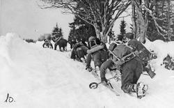 Menn, uniform, gevær, ski og skistaver, naturforhold. 
Frem