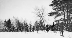 Menn, uniform, ski og skistaver, naturforhold. 
Skiløpertro