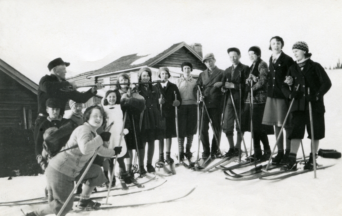 Gruppe mennesker på ski i S. Trysil (?). Hus i bakgrunnen.
Fra venstre: Helene Akre g. Kvile (1921), Jon Galaasen (1922), Hugo Bakken (1904 - 1985), Borghild Stenrud g. Skjæraasen (1912 - 1998), Elfrid Galaasen g. Busk (1919 - 2010), Kersti Galaasen f. Svendsen ( 1917 - 1995), Ingebjørg Galaasen g. Buflod (1915 - 1999), Målfrid Galaasen g. Hauge (1914), Haldis Kjernli g. Hegg (1912 - 1995), Martin Galaasen (1911), Ragnar Kvile (1915), Kjellaug Galaasen g. Karlsen (1915 - 1985), Ruth Grønnæs g. Grambo (1917), Hjørdis Bakken g. Bernts Grønland (1915)