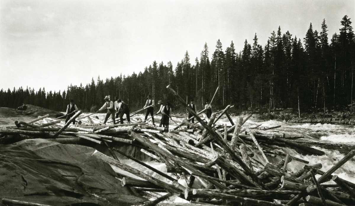 Fløtere stående på tømmerhaug i fossestryk. Sandkjellfossen (riksgrensa), s. Trysil.