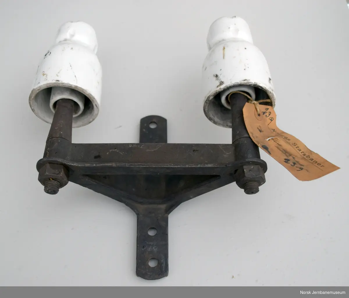 Dobbelt isolatorkrok, for sterkstrøm, veggfeste. 
Preussisk type, utviklet 1858 av Von Chauvin, kalt "Dobbelglocke"