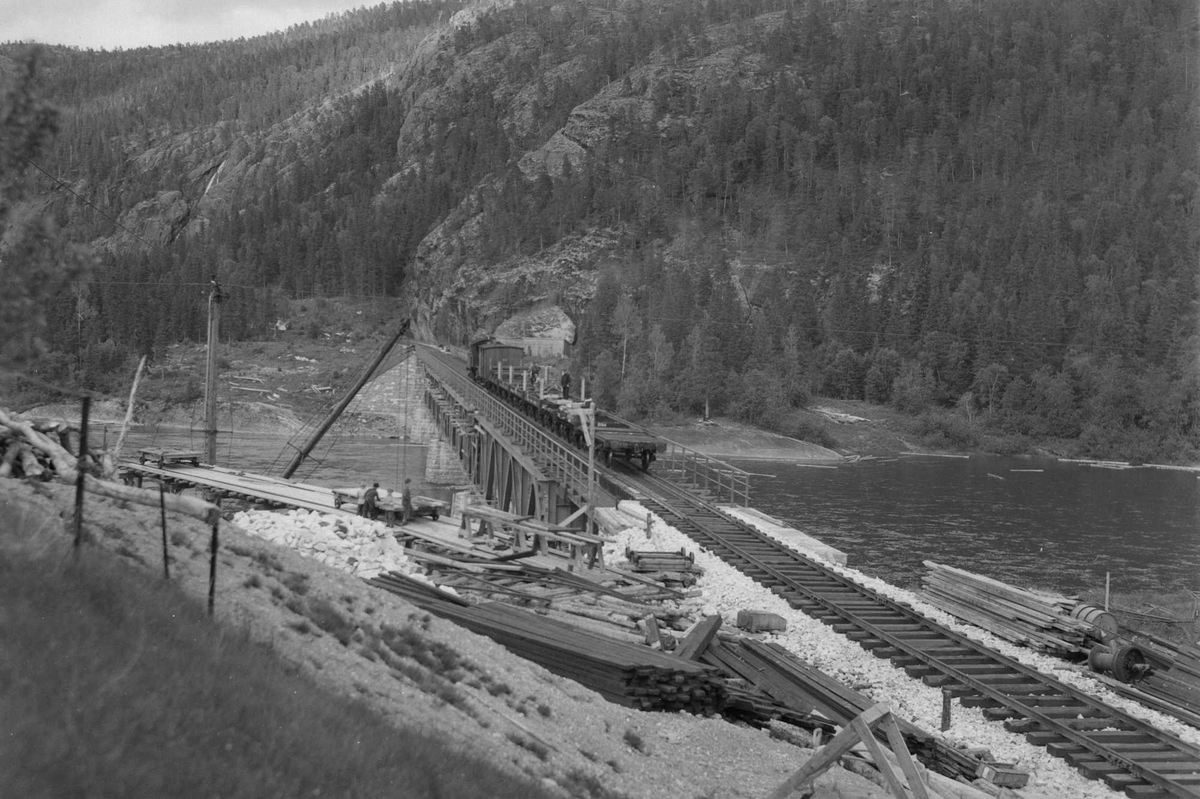 Under bygging av jernbanebrua ved Kvalfors .Lok med vogner på brua.
