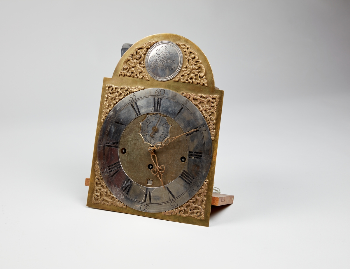 Rødmalt gulvur med forsiringer i form av nettverk, sped, stilisert akantus og rocaille. Urverket har sekund-, minutt- og datoviser og er forsynt med spillverk med to melodier.