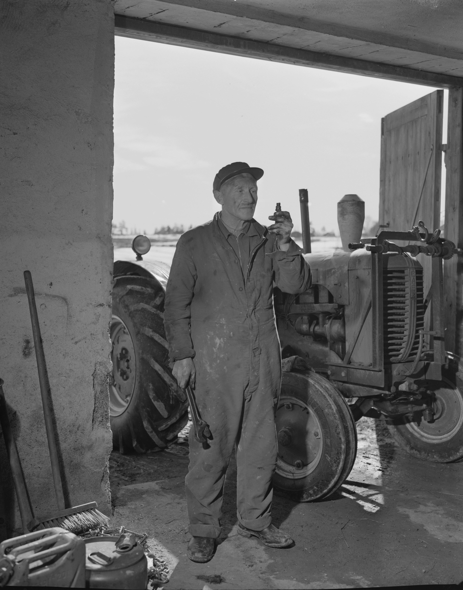Norsk landbruks jubileumsutstilling 1959. Mann med traktor i et verksted.