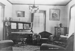 Piano, sofastoler, lyskrone, bilder.