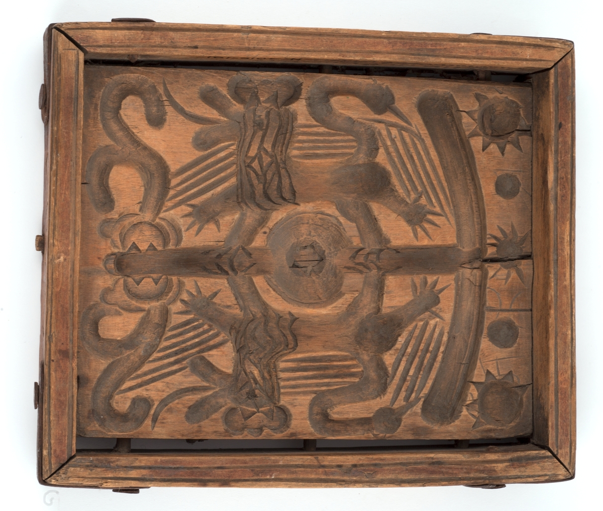 Firkantet kakeform med jernbeslag på hjørnene. Den ene siden av bunnen skåret med sol, måne, fabeldyr og et tre. Undersiden har blomster og rankedekor med 2 fugler. Litt skåret dekor på den andre siden.
Innskrift på den ene langsiden.