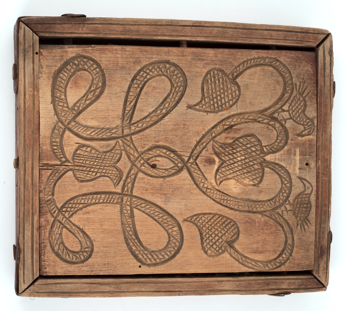 Firkantet kakeform med jernbeslag på hjørnene. Den ene siden av bunnen skåret med sol, måne, fabeldyr og et tre. Undersiden har blomster og rankedekor med 2 fugler. Litt skåret dekor på den andre siden.
Innskrift på den ene langsiden.