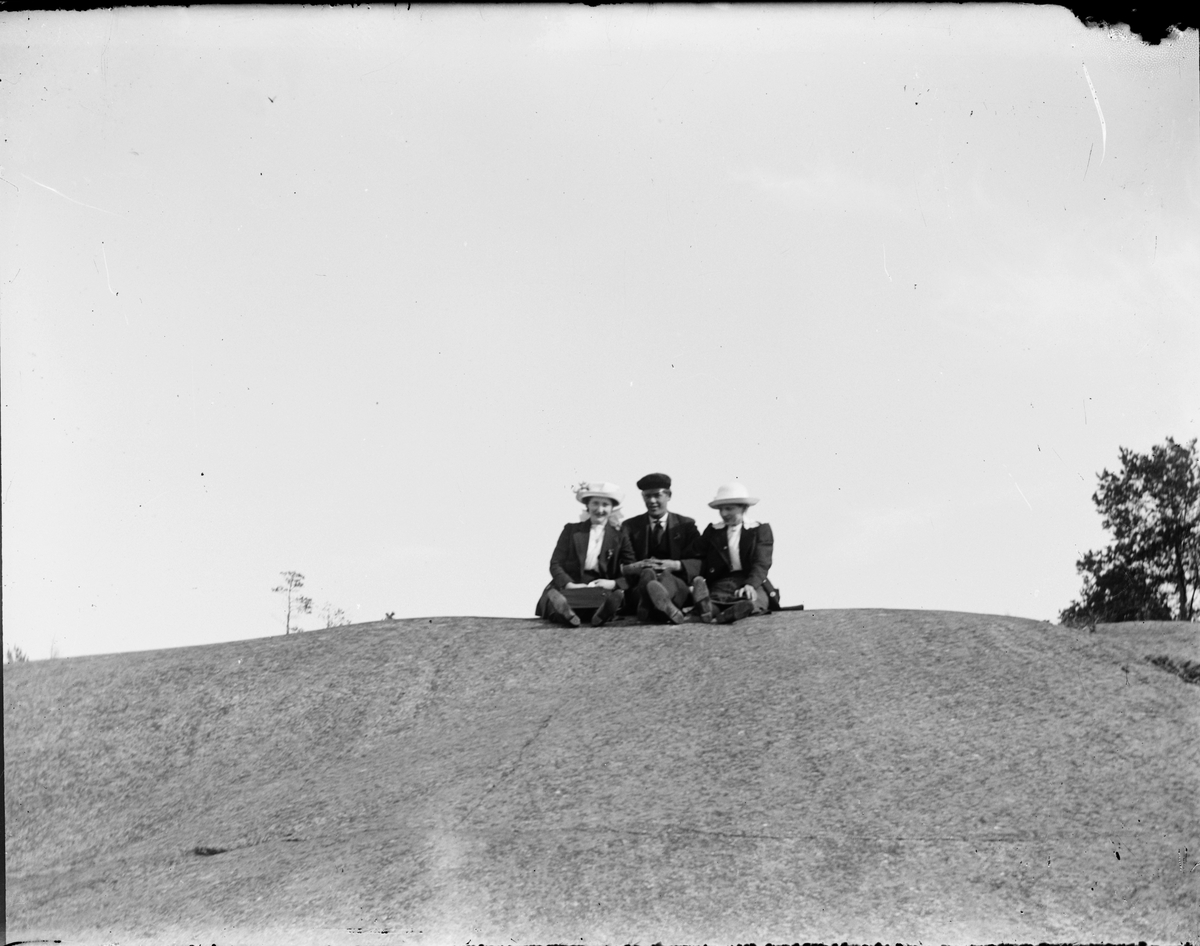Två kvinnor och en man sitter på berghäll, Östhammar, Uppland