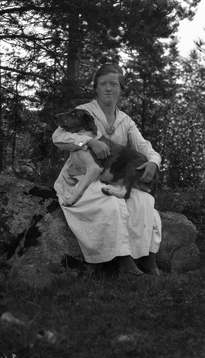 To portretter av Hanna Birgitte Olsen (f. Martinsen Sanden). På det første bildet sittende på en stor stein med en hund på fanget, på det andre stående  og i helfigur foran noen trær.