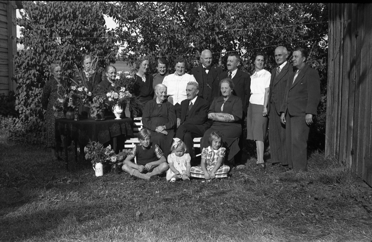 Antatt familieportrett tatt ved Dorte Hermansdatter Grønlis 90-års jubileum. Noen av personene er identifisert. Jubilanten sitter til venstre på krakken, og til høyre for henne ektemannen Mads Grønli. Lengst til venstre bak står Lina Grønli (svigerdatter). I midten bakerst med lys bluse står Dora Daarstad (barnebarn, f.Trannum), dernest hennes mann Einar Daarstad, og videre Jens Grønli, jubilantens sønn g.m. Lina. De øvrige er ikke identifisert.