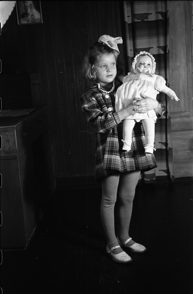 Portrett av en uidentifisert jentunge med dukke. Serie på sju bilder.