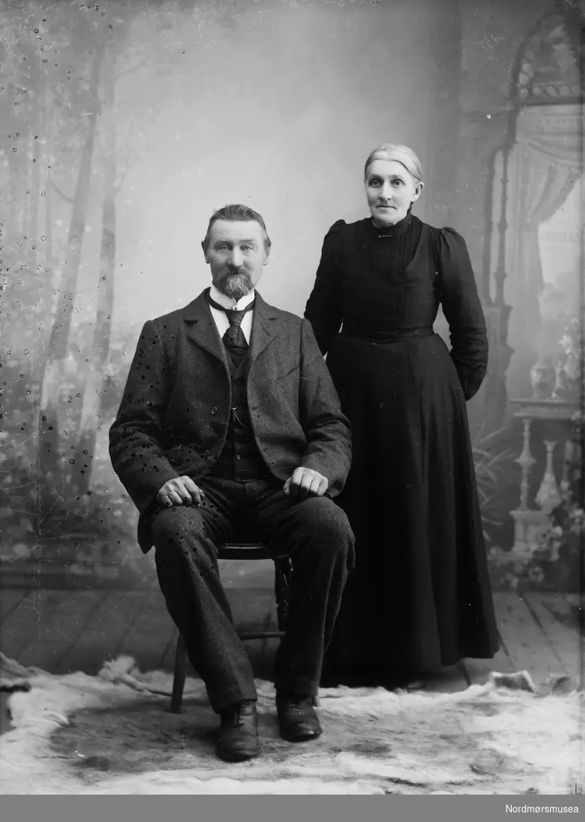 Eldre ektepar. Portrett av eldre par, personene er Anders Evens. Snøva (1848 - 1925) og kona Marit Olsdtr. f. Svisdal (1845 - 1914). Dette er de samme som på bilde med lsign. SU-L01.0014, men her er det blitt retusjert ein del.