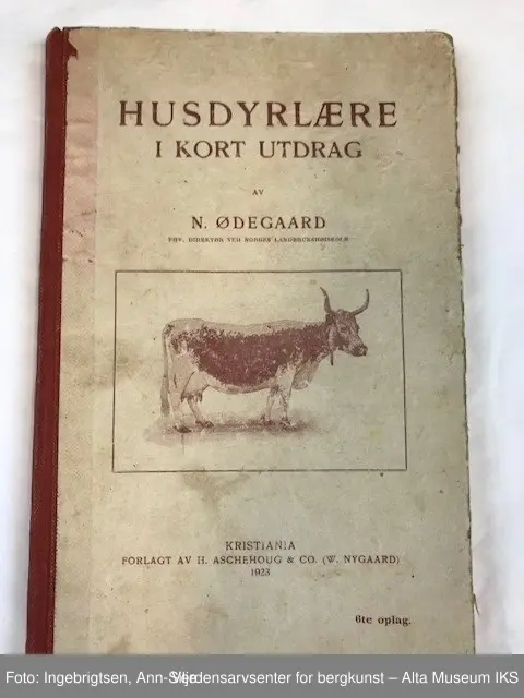 Bok med rød rygg og trykk på permene. På frontpermen er det et motiv av en ku av rasen fjordfe(?).