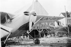 Fly på flystripa i Kaltdalen. Fjøs og hus i bakgrunnen.