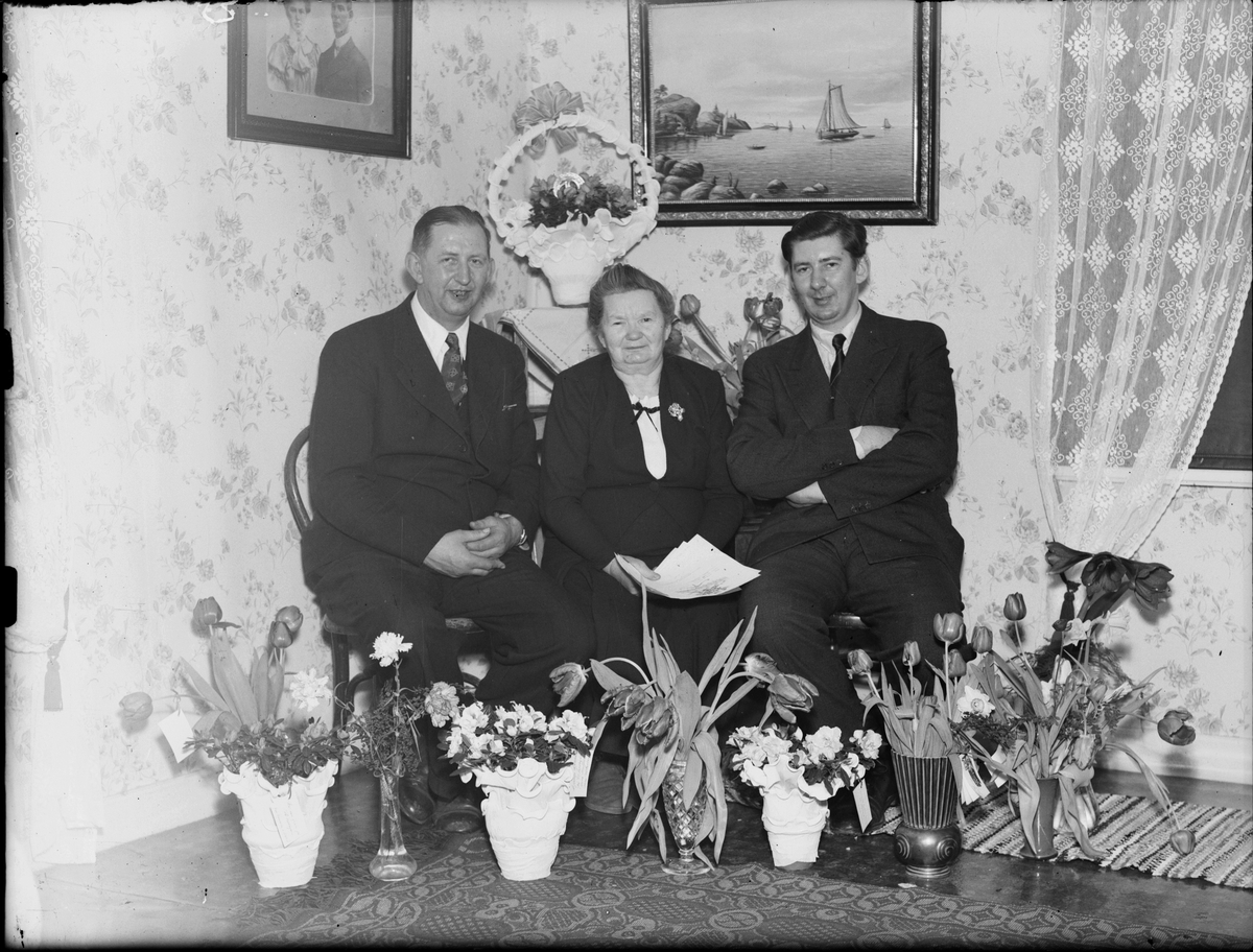 Hotellägare Ivar Janssons fru och två män omgivna av blommor, Östhammar, Uppland
