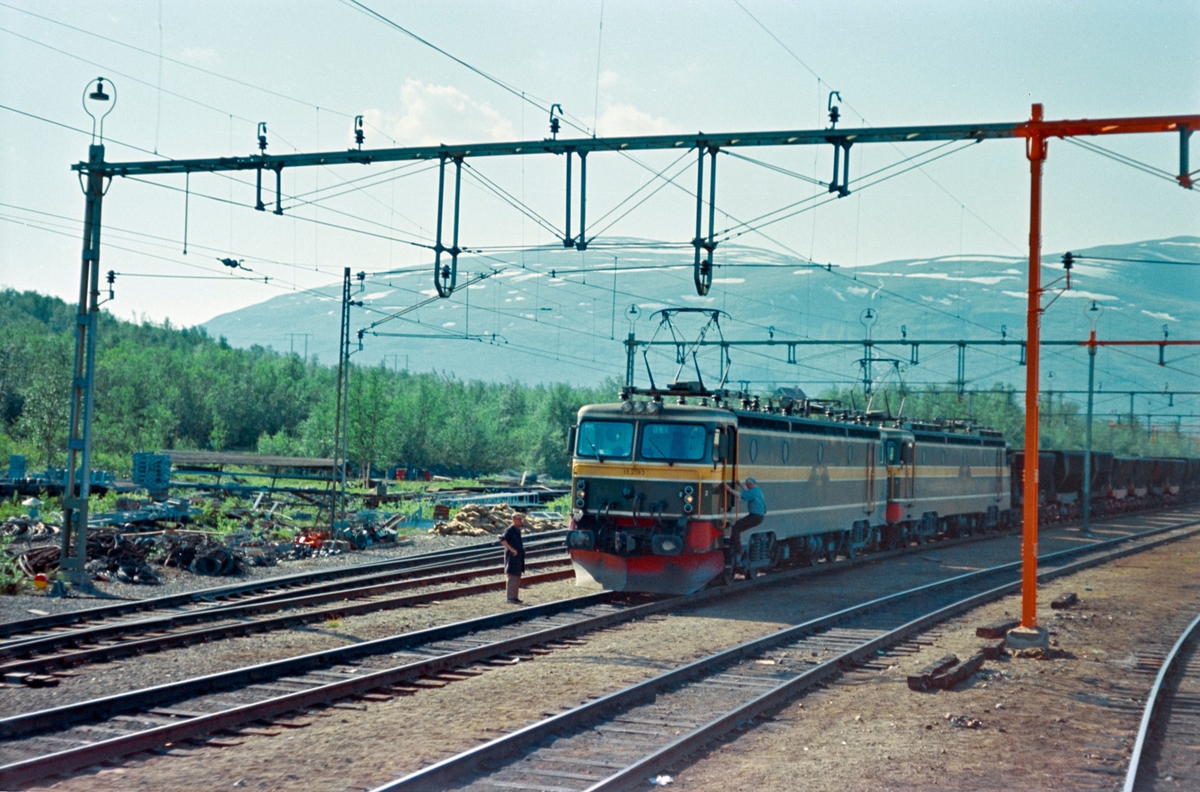 Tog med tomme malmvogner i Vassijaure på Malmbanan mellom Riksgrensen og Kiruna. Toget trekkes av to av NSBs elektriske lokomotiver type El 15, nærmest  nr. 2193.