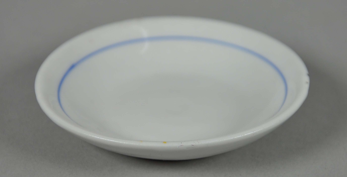 Asjett av glassert keramikk, med oppstående kant. Innenfor randen går det en blå stripe.