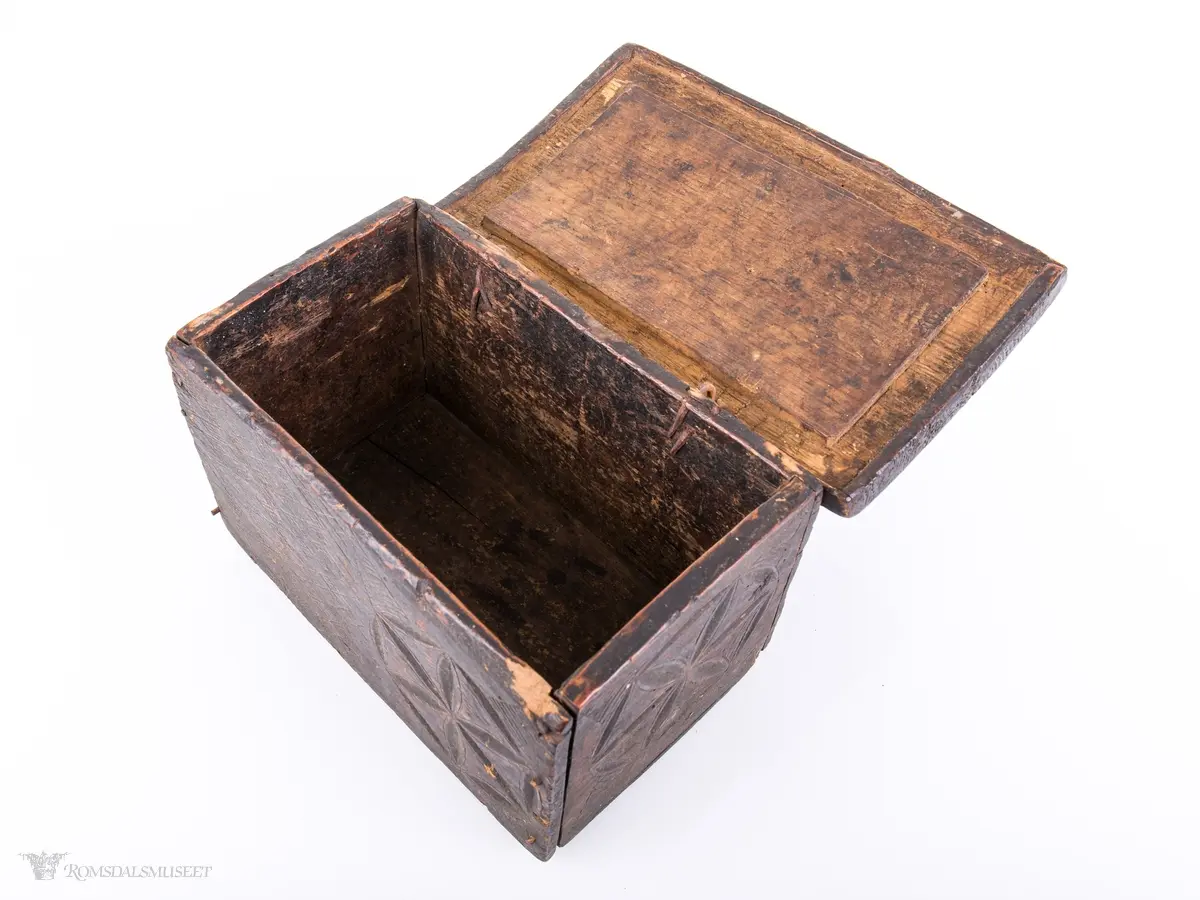 Seksbladsroser i karveskurd. 2 bak, en i front og en på hver korside. Rissede dekorfelt omkranser motivene.