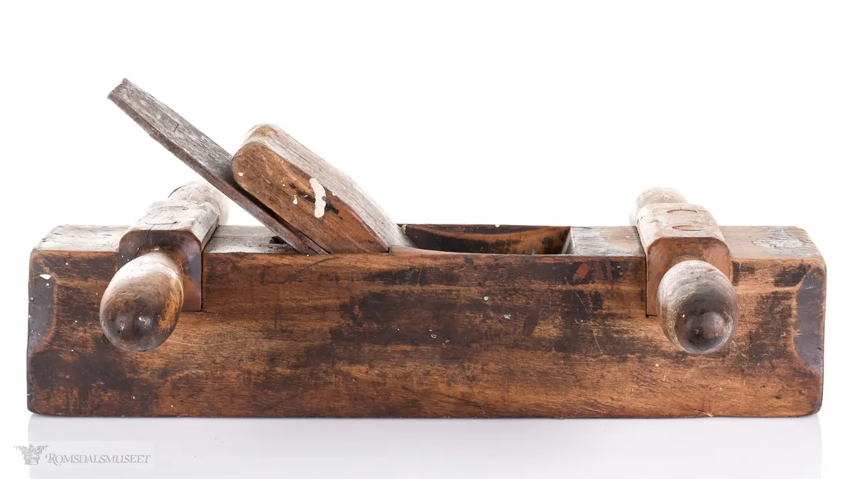 Oksehøvel i tre med rektangulær høvelstokk. Sponhus på toppen med høveljern med klaff og kile. Knekt av tre slått inn i bakkant.