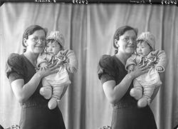 Portrett. Familiegruppe på to. Kvinne med briller og lite ba