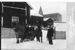Gruppe med,hest og sluffe. Gol kjyrkje i bakgrunnen.