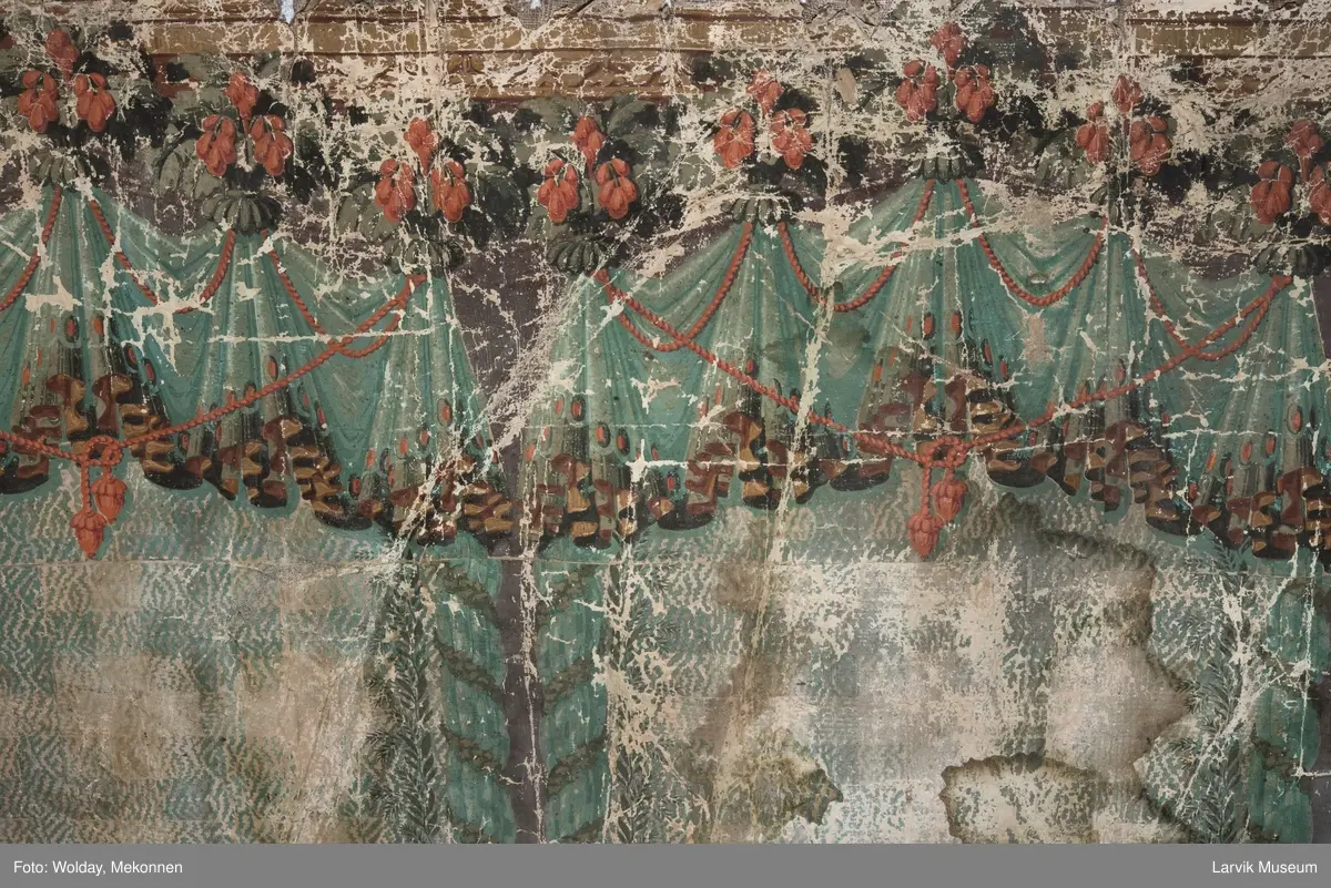 |Tapeten er påmalt tapetborder og brystning. Fra Hovland gård i Larvik.
Den øverste, brede borden: Gerlander/draperi med blomsterranker.
Den nederste, smalere borden: Tekstilbord med blomster. Øver døren til høyre: Stillebenmotiv med blomster og frukt.