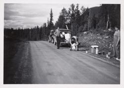 Familie med bil i en veikant. Bildet er tatt under en feriet