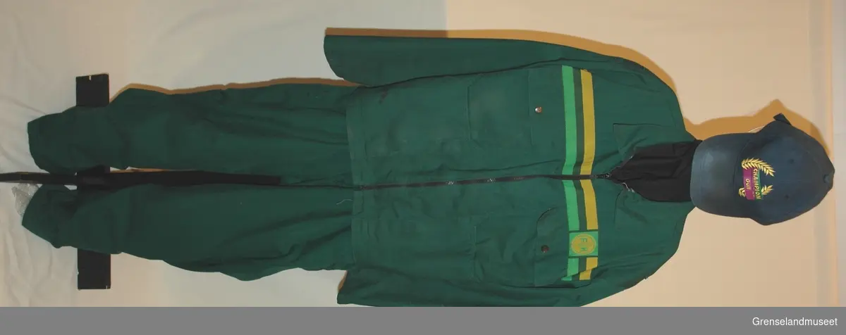 Kjeledress i tre deler, bukse, jakke, skyggelue. jakke st. 54, grønn med gul og lys grønn stripe, bukse grønn, skyggelue blå, st. 59.
Syntetisk stoff