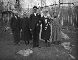 Brudeparet står ute antagelig sammen med foreldrene. Brudgom