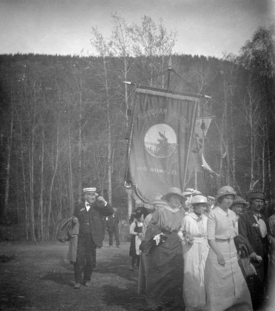 Kvinner i spissen for opptog. Bak fane med påskrift Ringebu Mandskor 23 januar 1914. Negativet halvert