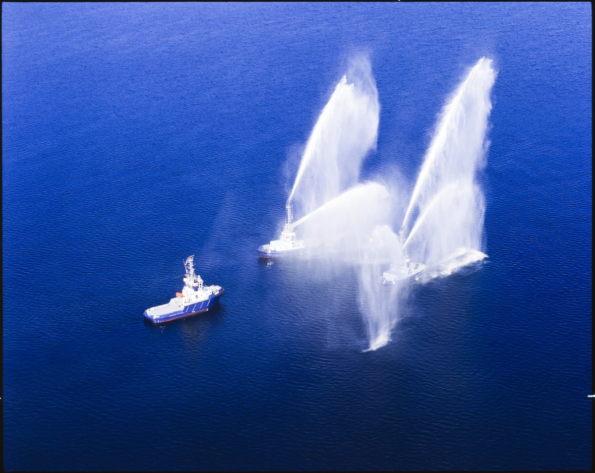 Østensjøs taubåter "Velox", "Pax" og "Dux" har en oppvisning hvor to av båtene spruter med vann for den tredje båten.