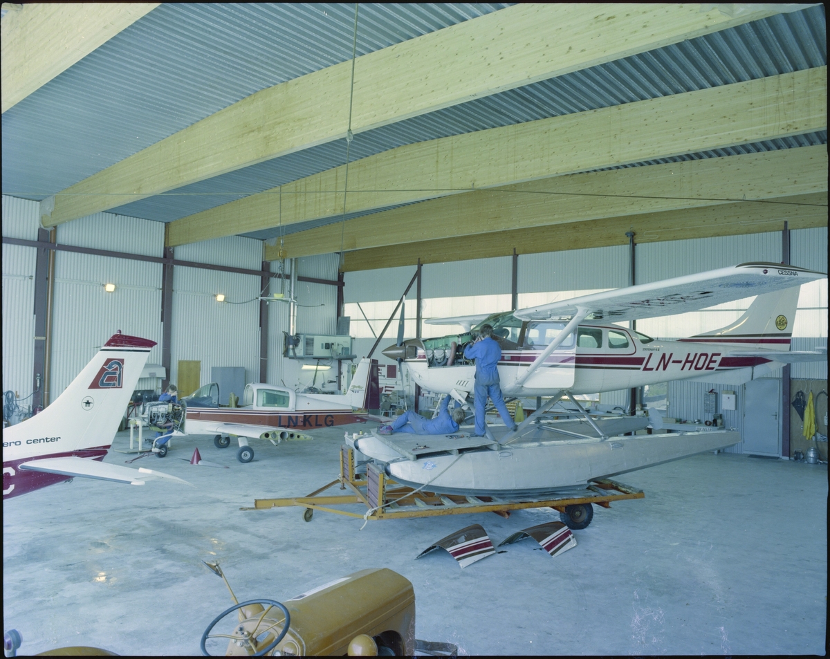 2 menn utfører service på et av "Coast Aero Center" sine sjøfly i en hangar på Helganes.