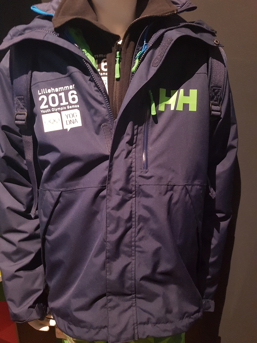 Mørkeblå jakke med elementer fra designprogrammet for Ungdoms-OL på Lillehammer 2016 nederst på ryggen, og emblemet for lekene på høyre bryst, og logo for Helly Hansen på venstre bryst.
