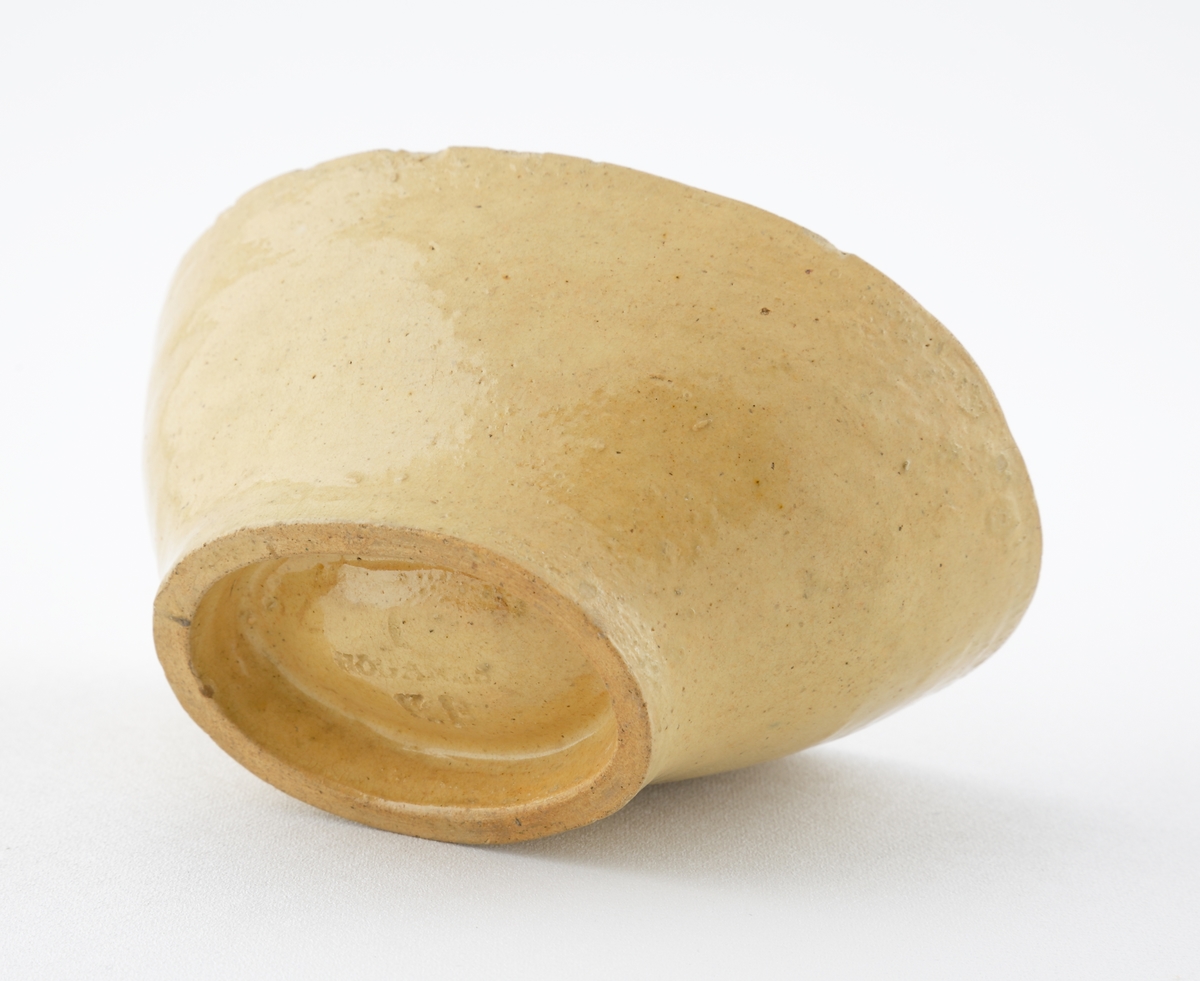 Aladåbform i keramik. 
Oval modell med räfflade kanter, överst en palmettbård. I botten en inpräglad druvklase.
Honungsgul glasyr.