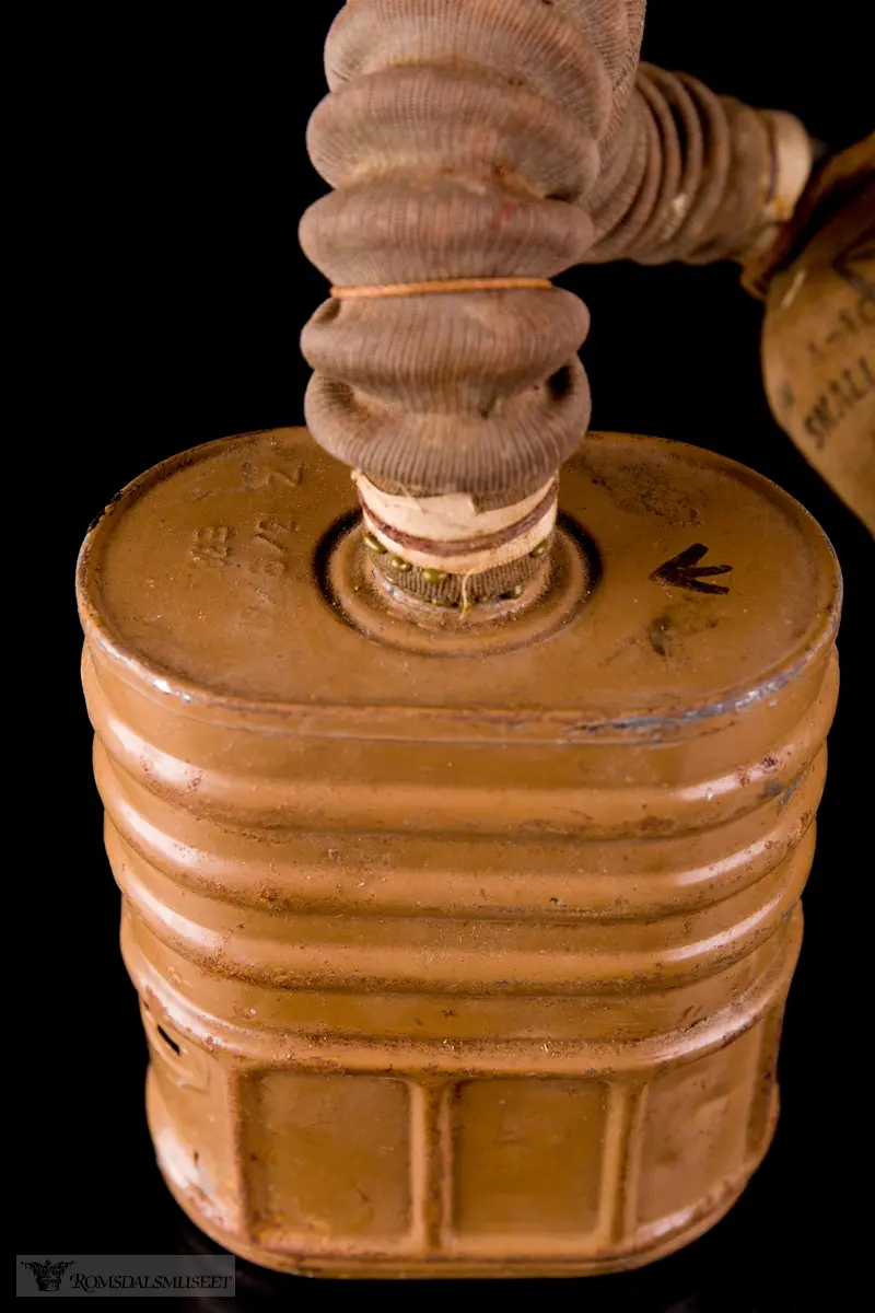 Britisk gassmaske brukt under andre verdenskrig. Ansiktsstykket består av tekstilbelagt gummi. En bøyelig slange går fra den runde, perforerte utlbåsningsventilen til et ovalt, tønneformet filter. Festestropper i gummi med bakhodestykke av lær.