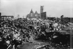 Namsos. En person foran et bombehull. Kirkeruinene i bakgrun