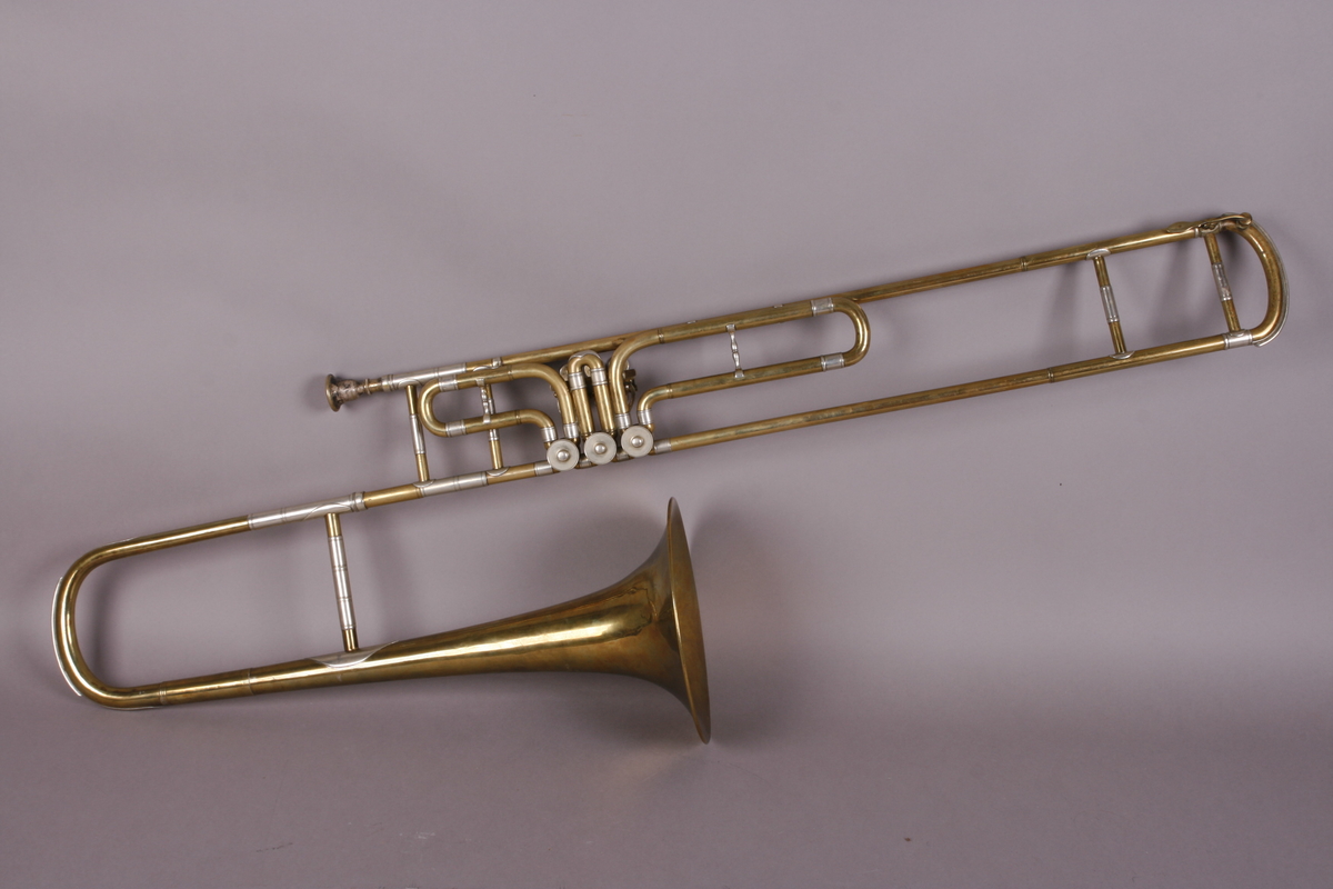 Ventilbasun, eller trombone, i messing, med dreieventiler. Tilhørende munnstykke.