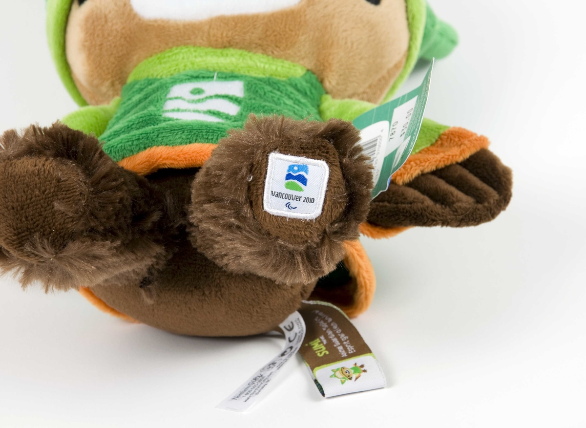 Flerfarget figur av Sumi; en av maskotene for de olympiske vinterleker i Vancouver i 2010. Figuren har grønn genser/jakke og grønn lue. På jakken/genseren er det emblem for de olympiske vinterleker i Vancouver. 