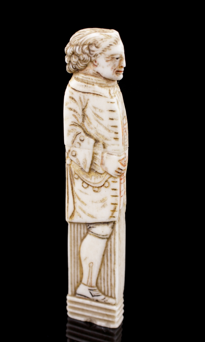 Nåletui, av ben.
Snidad och ristad dekor I form av en mansfigur i 1700-talskläder.
Saknar signatur/stämplar.
Svensk eller möjl. engelsk tillverkning.