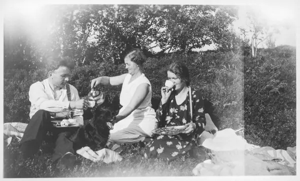 To kvinner, hund og en mann har kaffepause utendørs.