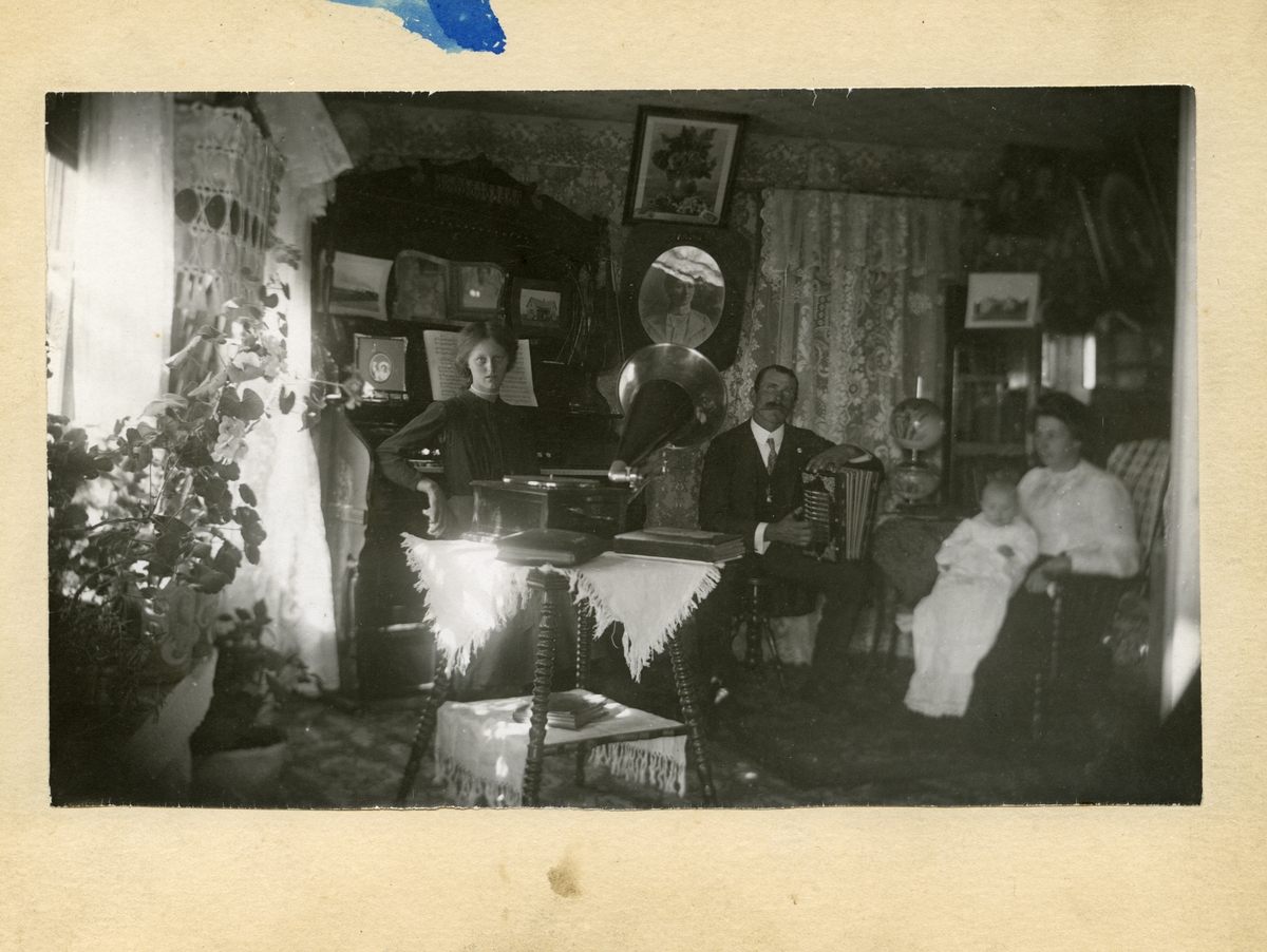 To kvinner, en mann og et spebarn avbildet i en stue.