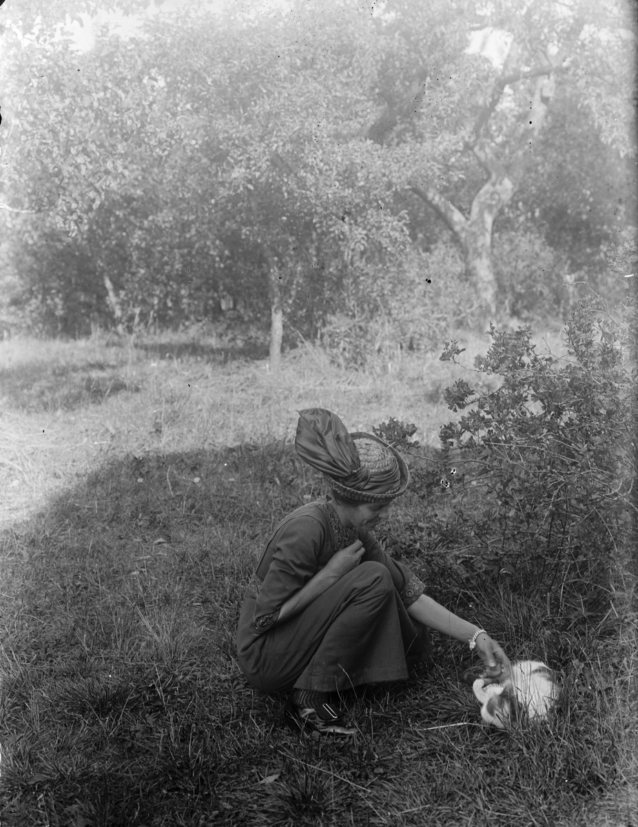 Hildegard Pettersson med katt i trädgården, Sävasta, Altuna socken, Uppland