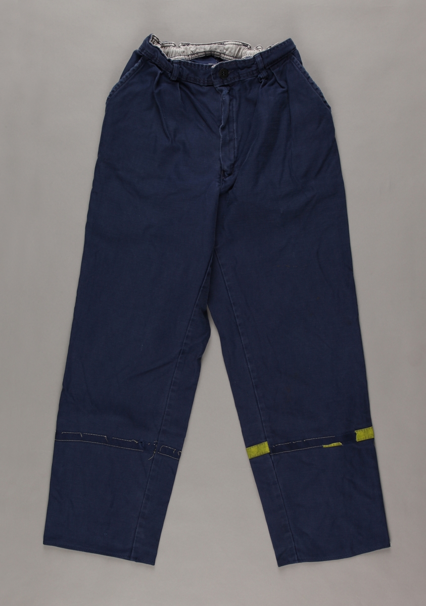 Blå bukse med gult refleksband rundt begge bein, dvs: heilt avrive/utslite på høgre bein og dels på venstre.   Storleik 48